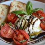 Burrata Caprese salad with creamy burrata cheese, ripe tomatoes, fresh basil, balsamic glaze, and toasted bread slices on a white plate.